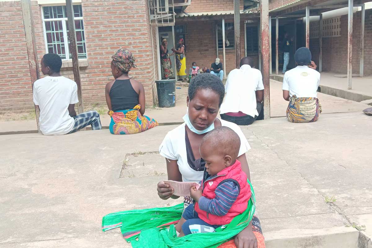 Patuma Mauwa sitting with her last born child who survived Typhoid fever, Ndirande Health Center in Blantyre. Credit: Benson Kunchezera